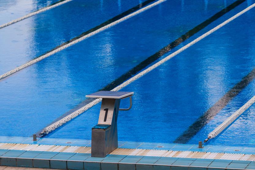 Startblock mit der Nummer 1 am Beckenrand eines Schwimmbeckens mit blauen Wasserbahnen im Hintergrund.